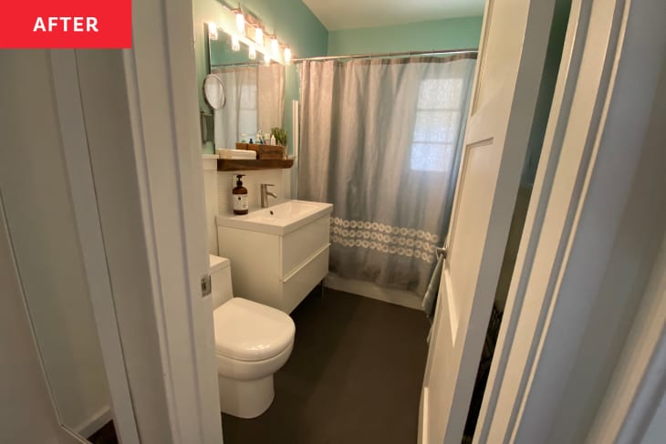 After: A bathroom with blue-green walls, a white door, and white drawers below the sink