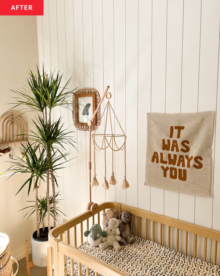 After: a nursery with white paneled walls and art hanging above a crib