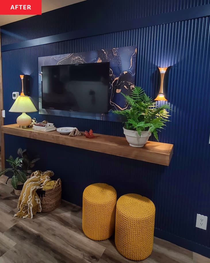 After: a dark blue wall with a tv mounted to it above a wooden shelf
