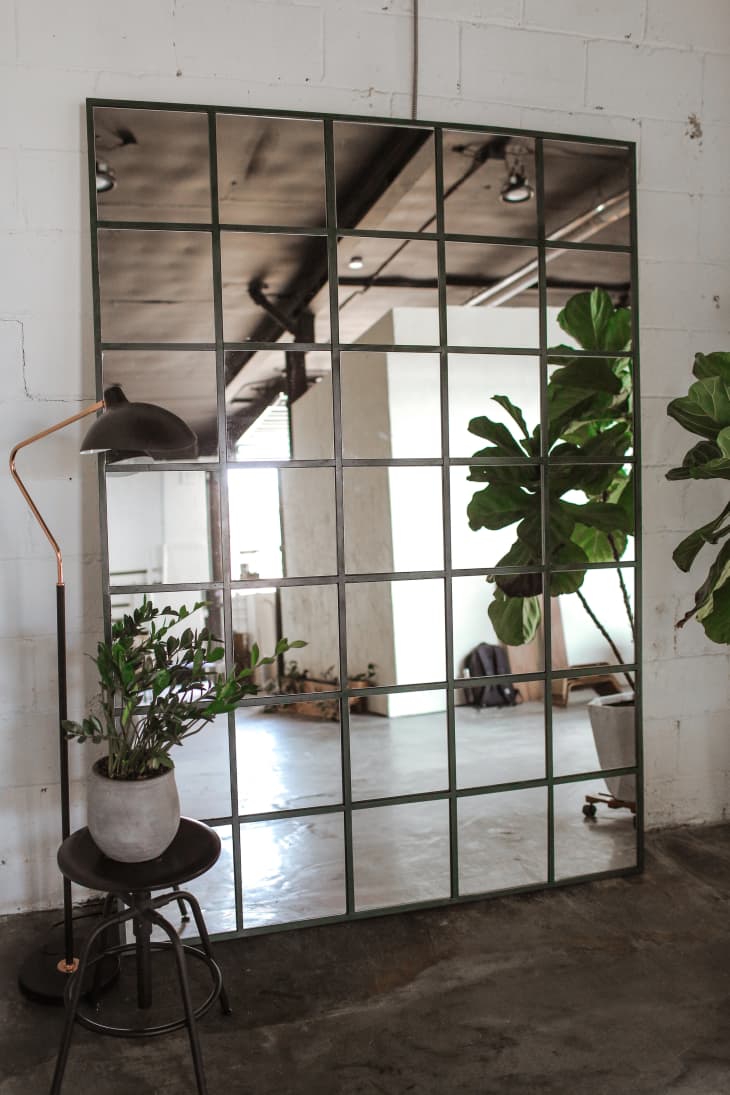 Large industrial-style gridded mirror leaning against a white wall