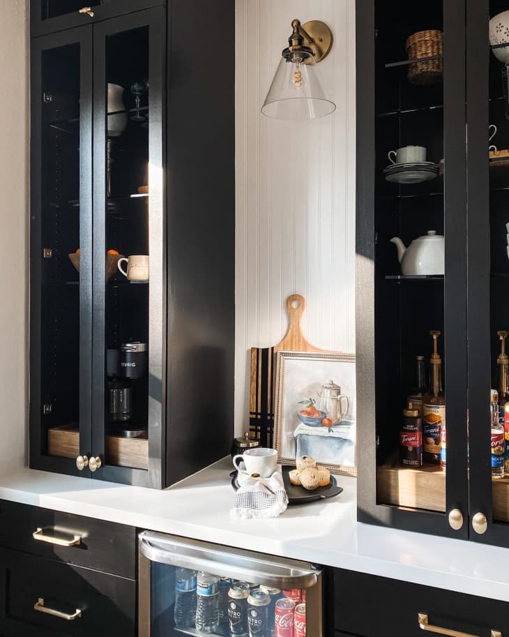 a black coffee bar with gold handles on the drawers and a pull out tray for the coffee maker, etc