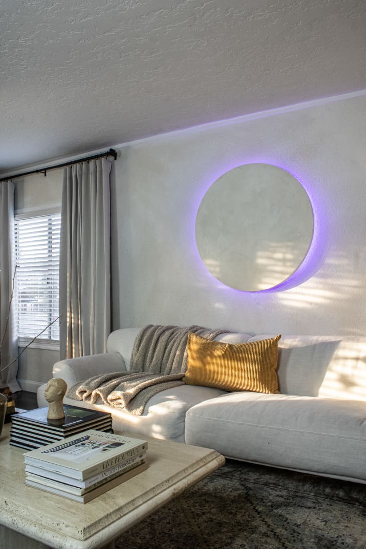 A purple circle light above a white couch