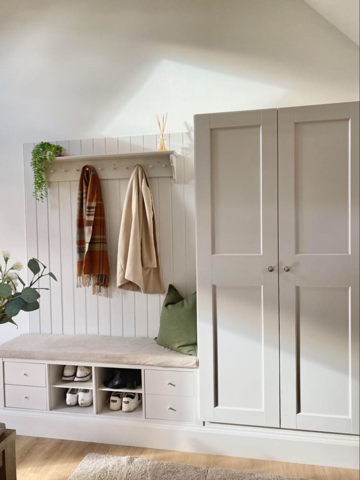 A white cupboard by a white hook above a white bench