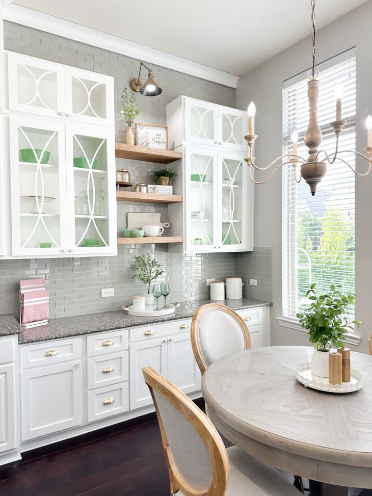 White kitchen cabinets with mullions behind round dining table