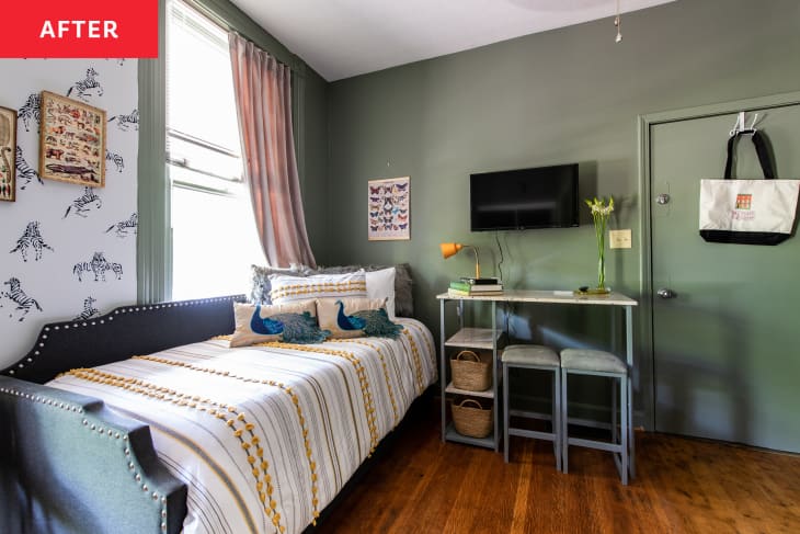 Small bedroom space with green painted walls and a small work desk next to a daybed.