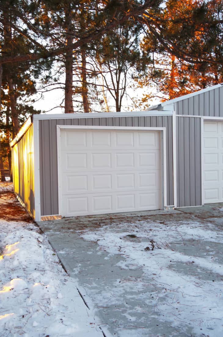 One-car extension on garage, with a white door and gray siding.