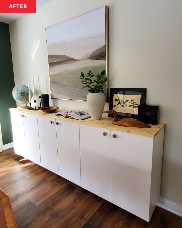 floating credenza with white cabinets, wood top. Objets, candles, a globe, framed art on top. Large painting above
