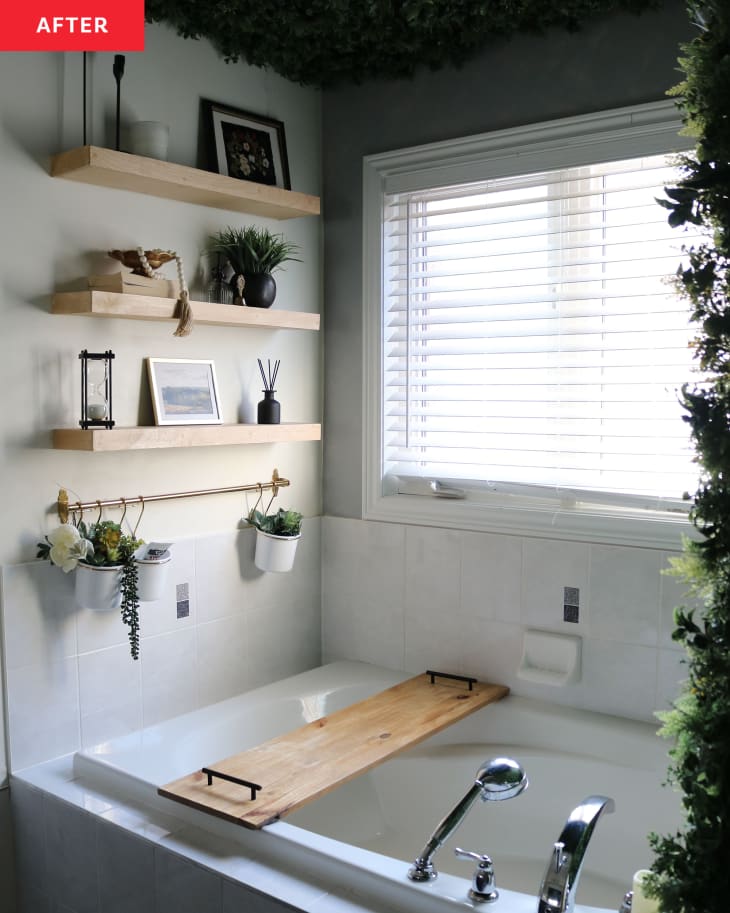 Wooden shelves filled with props near bathtub in newly renovated bathroom.