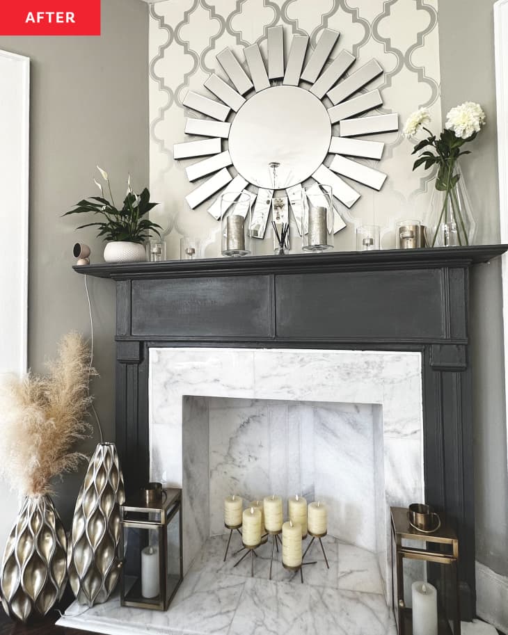 Fireplace after redecorating by painting manel black and adding silver wallpaper, sunburst mirror, various vases and candles inside fireplace.