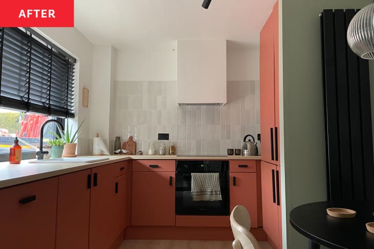 Kitchen with coral colored cabinets and light grey backsplash after renovation.