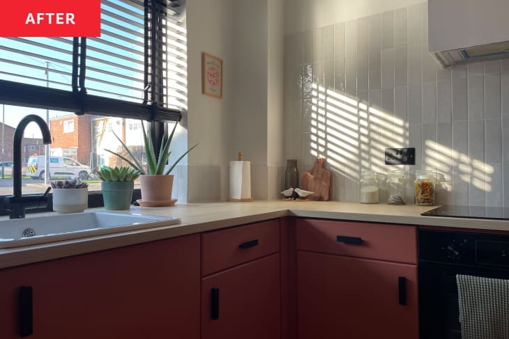 Kitchen with pink cabinets and grey tile backsplash after renovation.