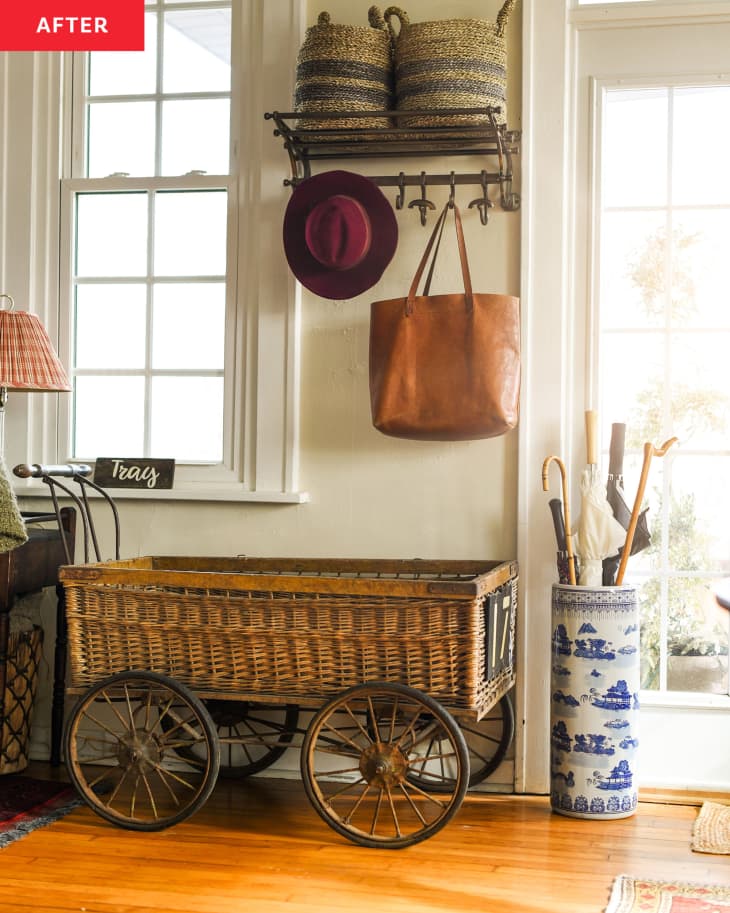 Living room after renovation: detail of entry area with shelf with storage baskets, hat and purse hooks, a ceramic umbrella holder, straw wagon