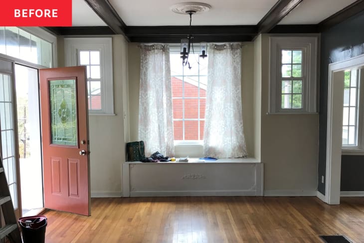 Living room before renovation: blue accent walls, white ceiling with exposed beams, no furnishings