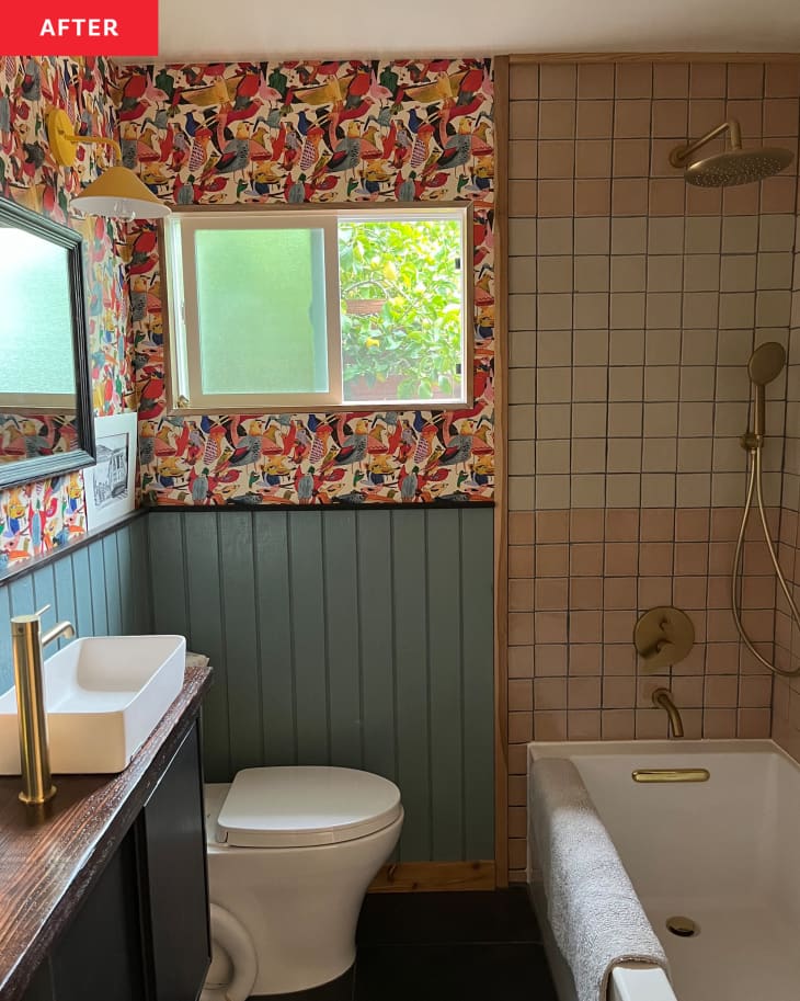 Bathroom with colorful bird wallpaper and blue wainscoting after renovation.