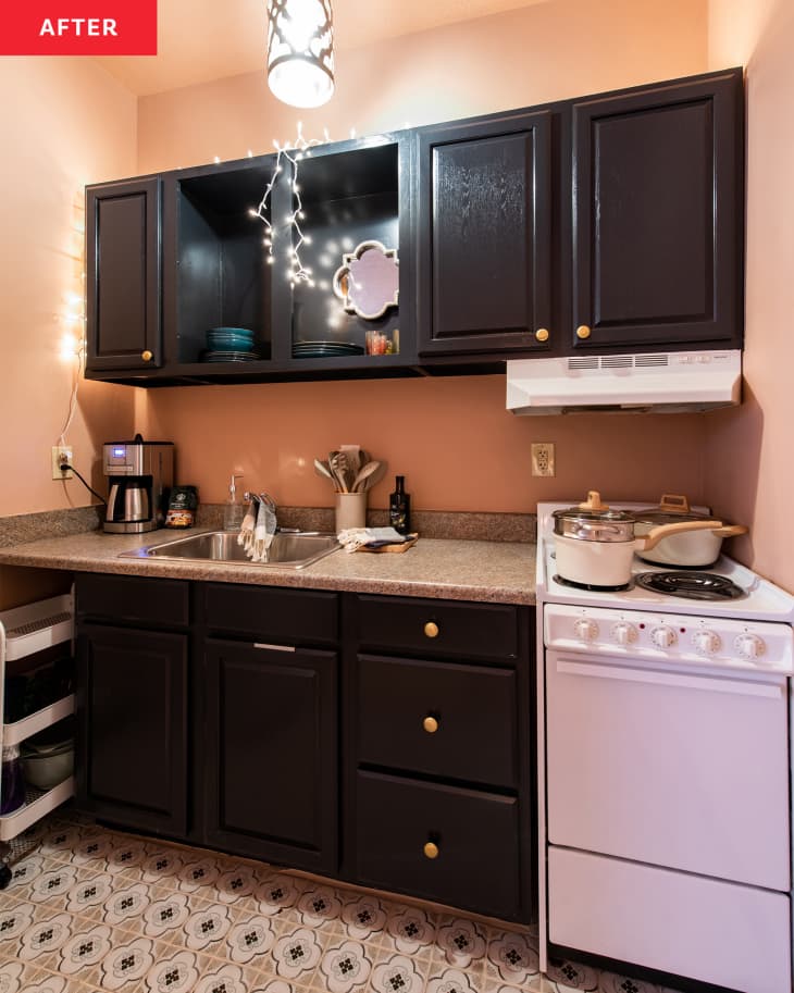 Kitchen after makeover. Pink walls, black cabinets, rolling storage shelves under counter, hanging lights, pink black and white tile or faux tiled floor