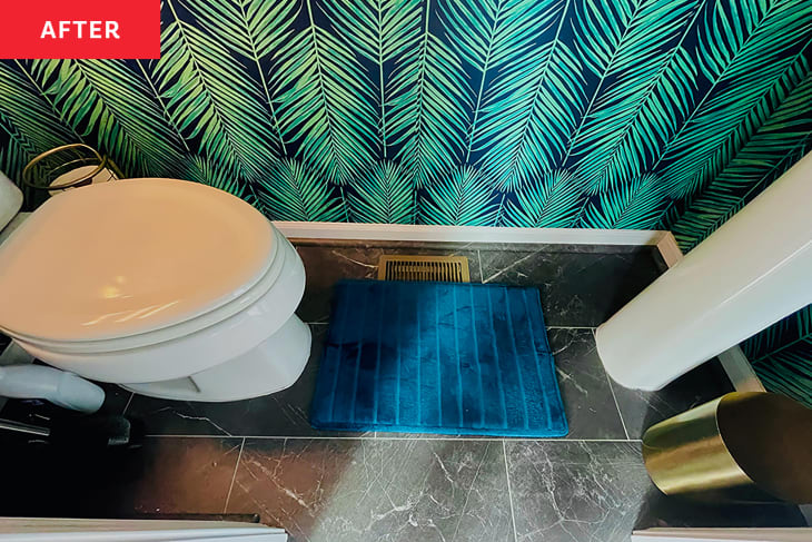 Blue bathmat in palm leaf motif bathroom.