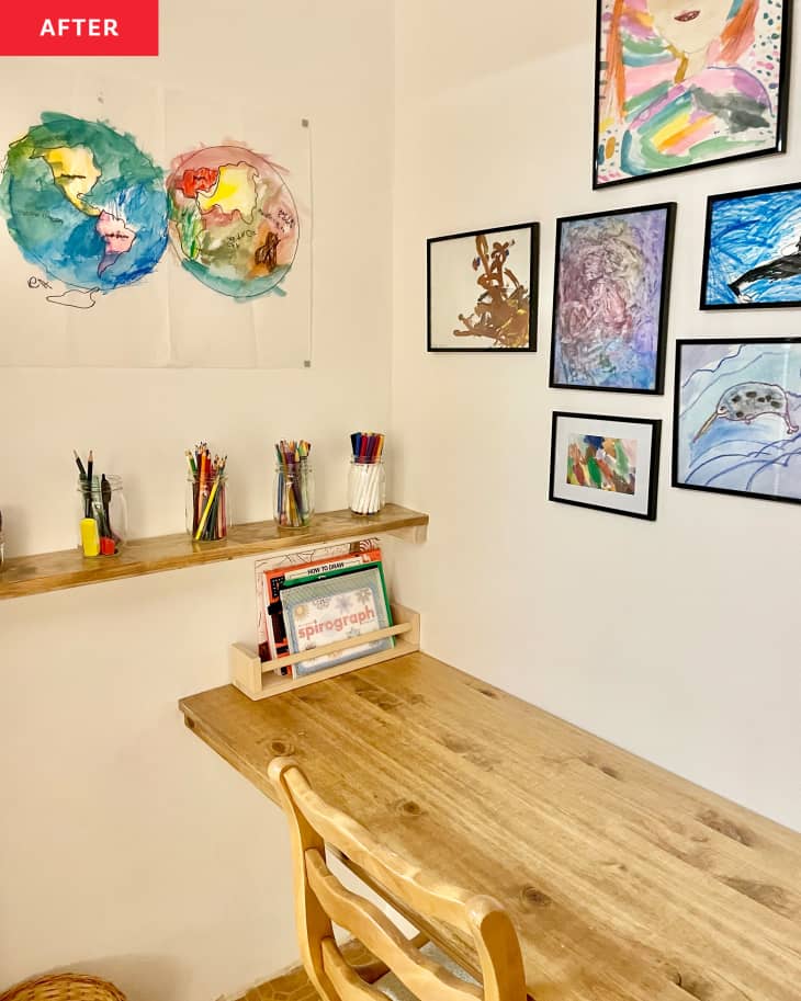 Closet after renovation, now a kids' art closet. Table across the width of the closet, 2 chairs, shelves on either side with lots of art supplies, framed kids' art on walls