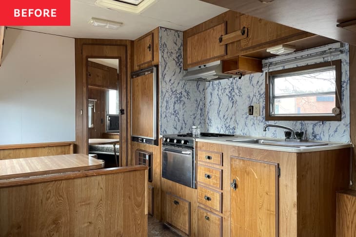 Camper kitchen with dark wood cabinets before renovation.