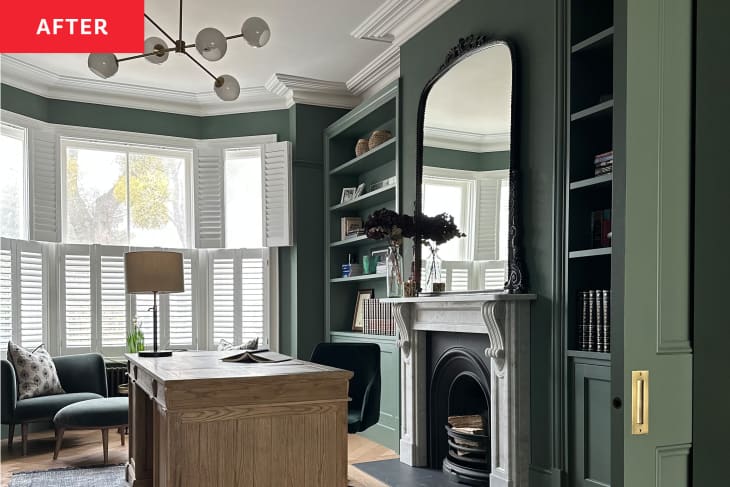 Home office after renovation: green walls and built-in shelves, wood desk, white fireplace with mirror above, sputnik style pendant light,