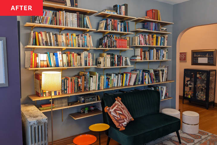 Bookshelves with gold brackets and velvet sofa in front after renovating.