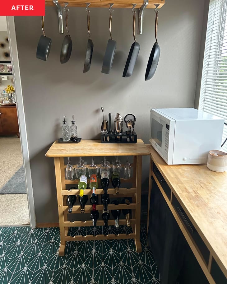 Bar cart in newly renovated kitchen with skillets and pots hanging above.