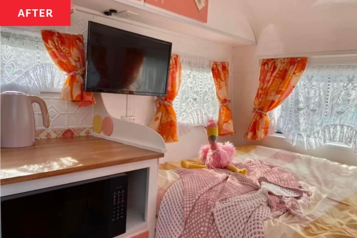 Inside of caravan/camper after renovation: coral and white paint, lot's of pops of pink, orange, fabric curtains