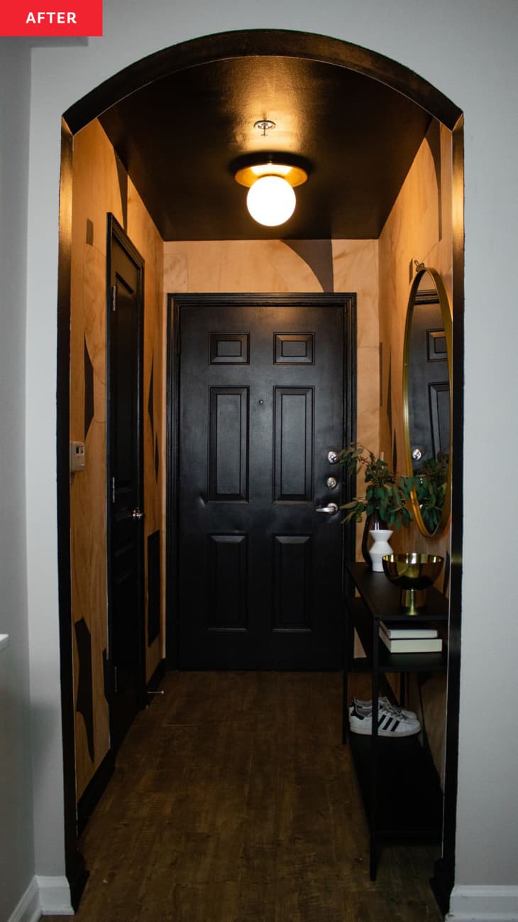 Entryway after makeover: gold textured paint with black accent shapes, black door, black ceiling, black console table