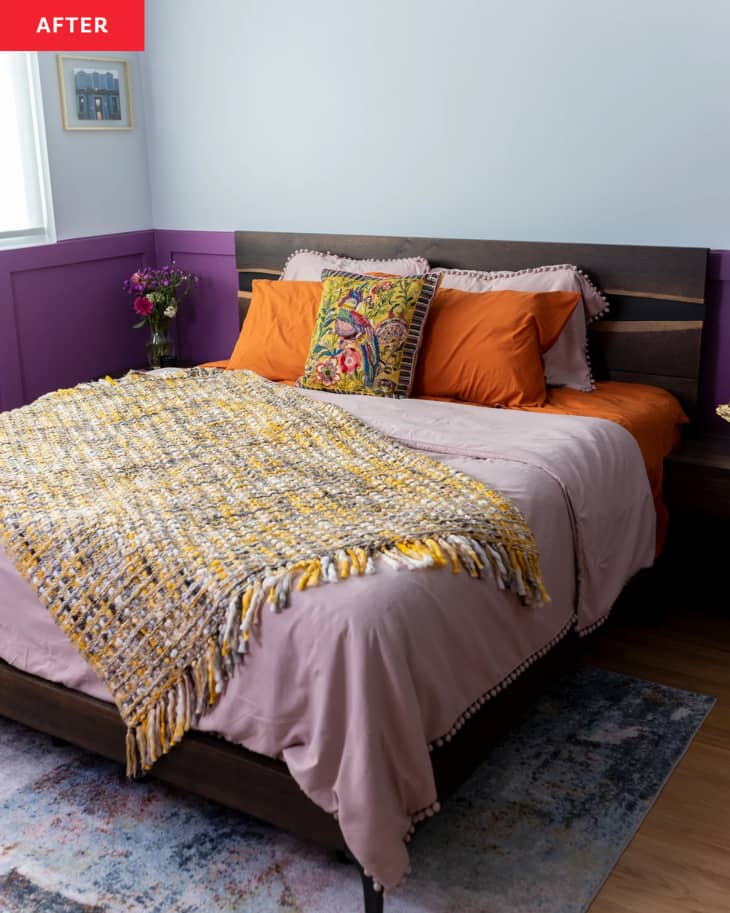 Neatly made bed with colorful accents in newly renovated bedroom.
