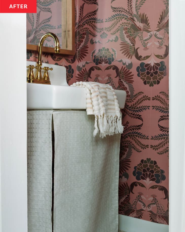 After: pink floral wallpaper in a bathroom with a gold faucet in a white sink