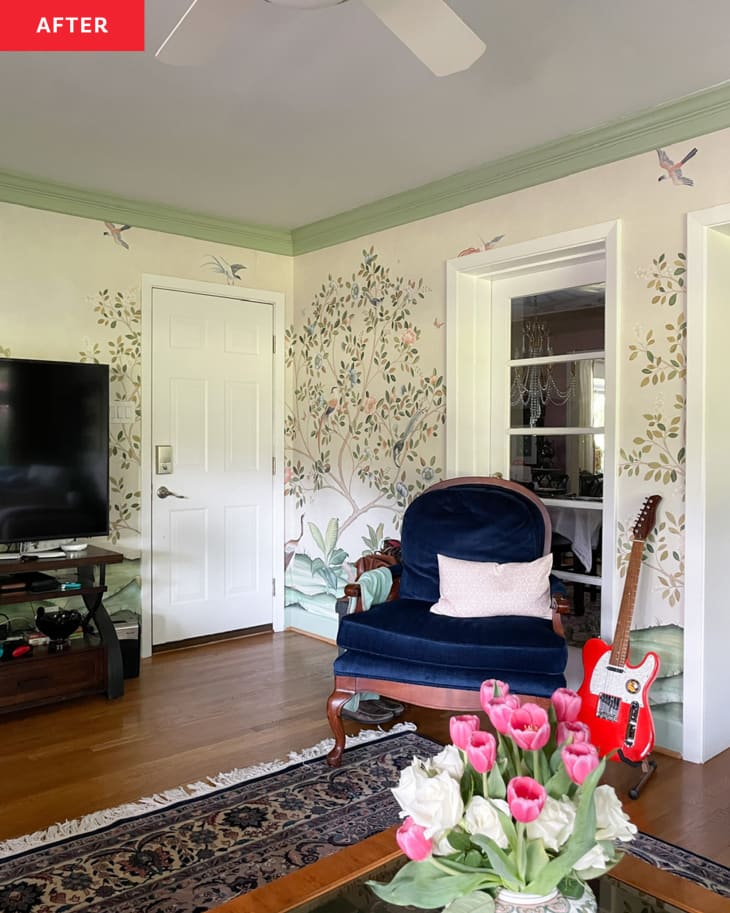 Living/family room with tree and bird wallpaper, green and white trim, navy blue armchair, electric guitar on floor