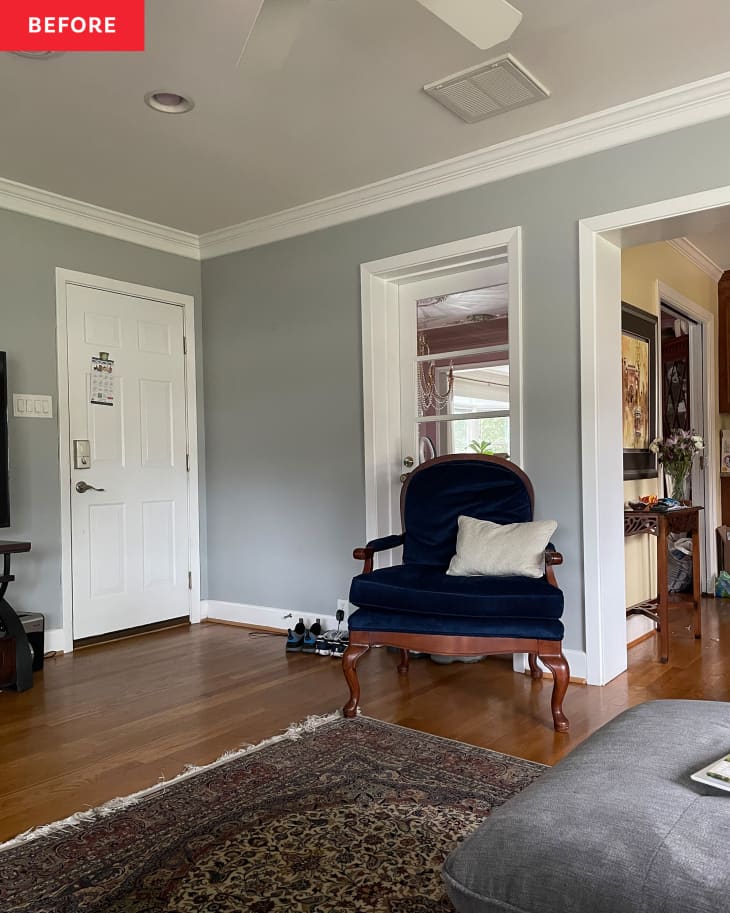 living/family room before makeover. gray walls with white trim, wood floor, navy armchair