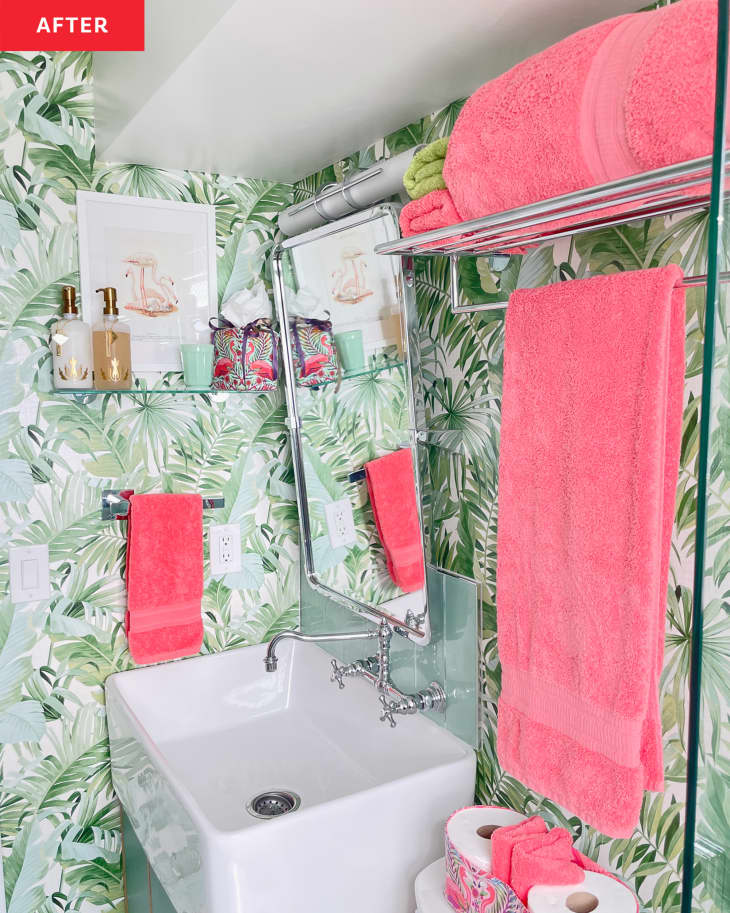 Green botanical wallpaper in bathroom with bright pink towels.