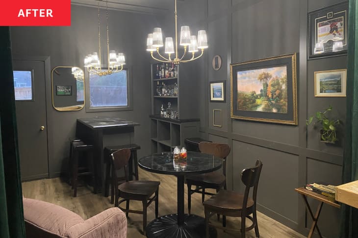 后:black speakeasy with old framed art on the walls, a bar in the corner and a round table under a hanging light