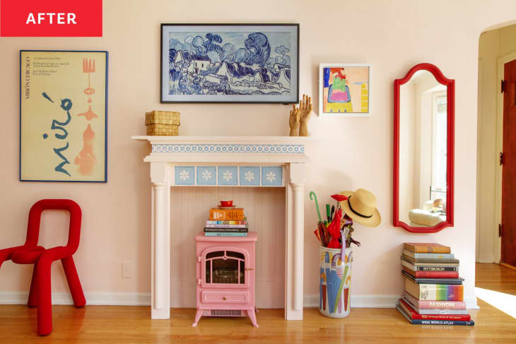 After: A pink fireplace surround with a pink electric fireplace in the hearth, set against a pink living room wall. There is art on either side of the faux fireplace, and a Frame TV hung above it with a blue and white landscape on display.