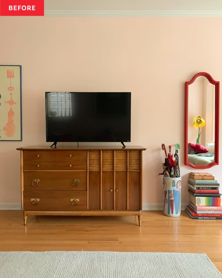 Before: Pink living room with a TV propped on a natural wood vintage sideboard in a medium brown tone.