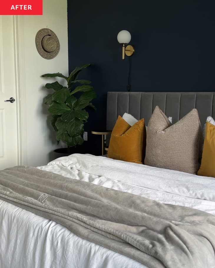 After: A bedroom with a blue wall and white wall with a plant in the corner by the bed