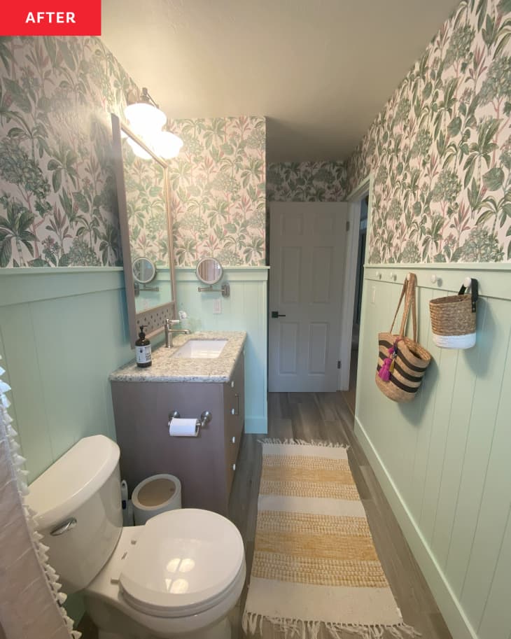 Newly renovated bathroom with green wainscoting and floral wallpaper.