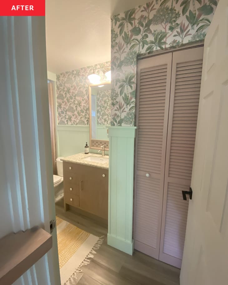 Mauve painted closet door in newly renovated bathroom with floral wallpaper and green wainscoting.