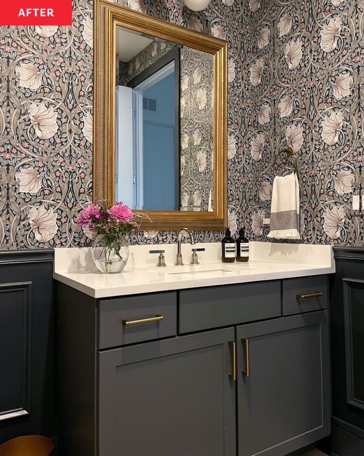 Dark vanity with light countertops in newly renovated bathroom with floral wallpaper.