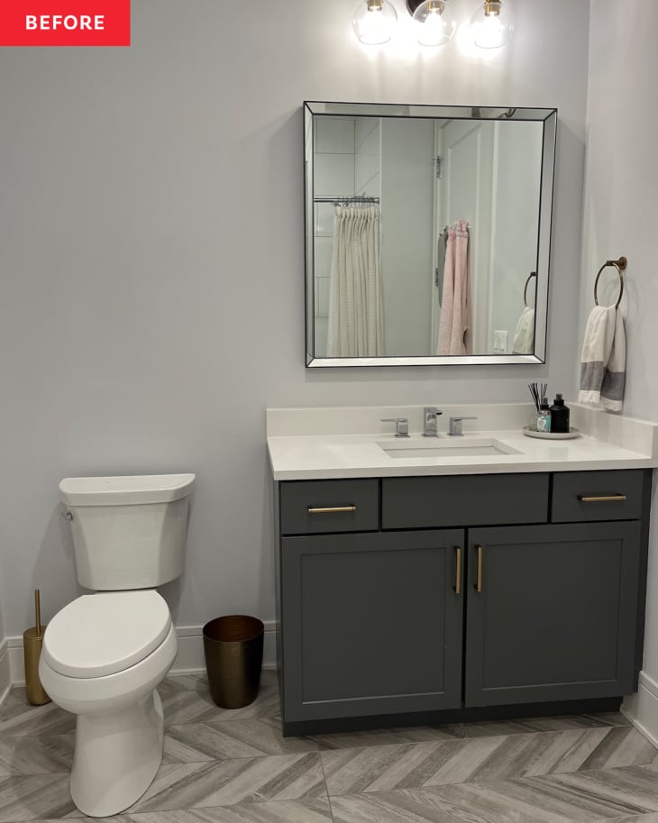 Light grey painted bathroom with dark vanity and beveled mirror before renovation.