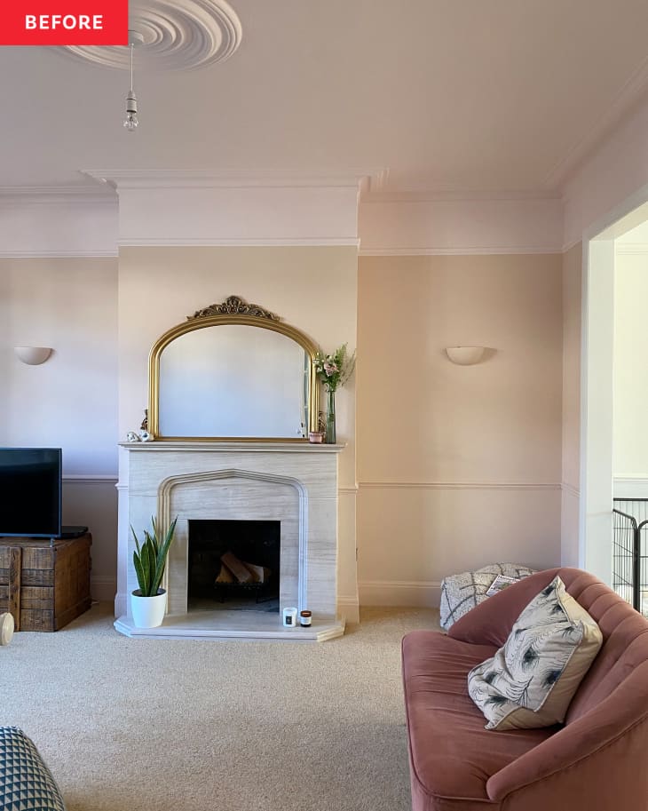 Vintage mirror over fireplace in light colored living room with pink sofa and carpeted floors.