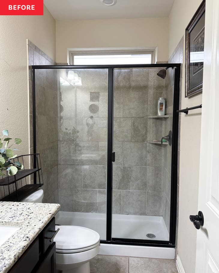 Black framed glass shower door in bathroom before renovation.