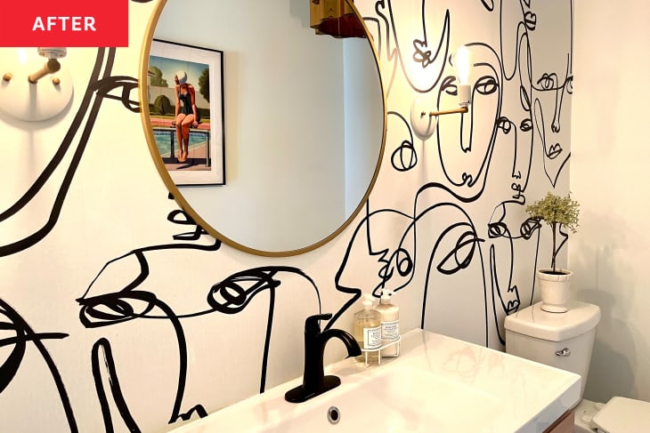 不wly renovated bathroom with black and white face doodle wall paper and sconces on either side of a round mirror.