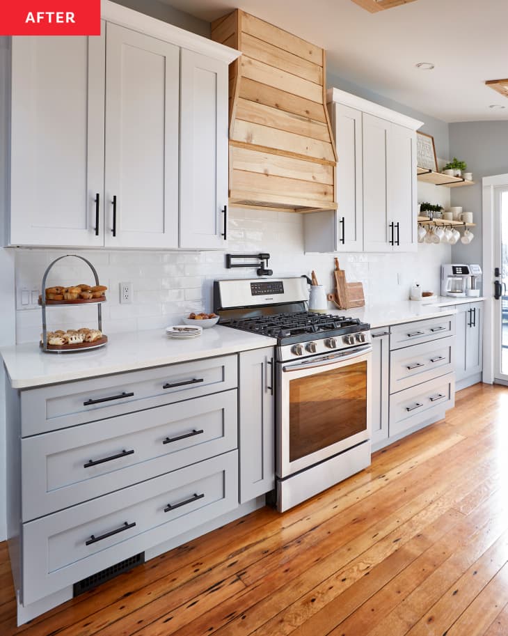 Kitchen after renovation: white and pale gray cabinets, wood accents, wood floors, new white tile backsplash,