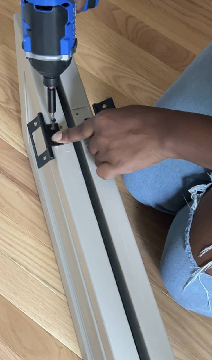 Using a drill to attach new hinges to the closet doors