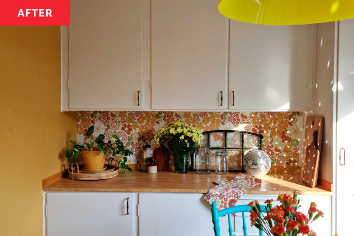 yellow round lighting fixture, flowers in pitcher, white cabinets wall to ceiling, wood counter, wood floors, disco ball, yellow flowers, tea towel, decorative window, plants