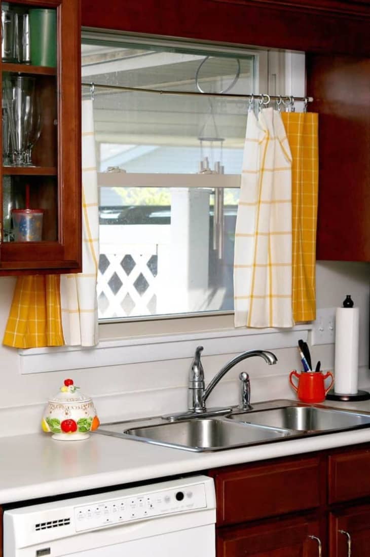 window over a kitchen sink with two yellow dish towel curtains from IKEA