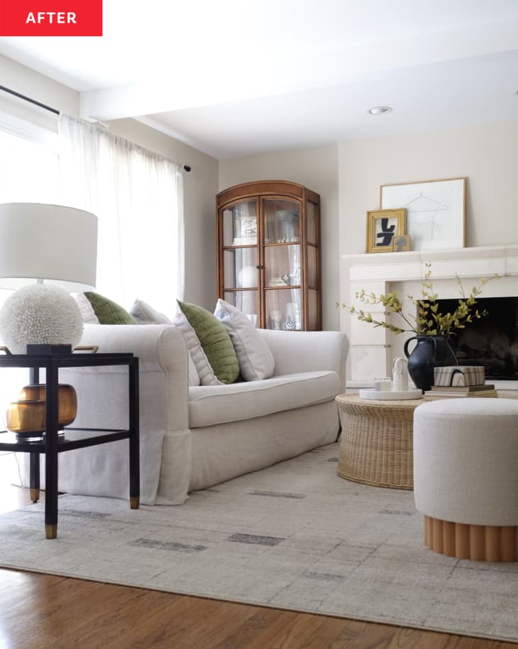 不utral colored living room with white sofa and wicker coffee table. Curio cabinet in nook beside fireplace.