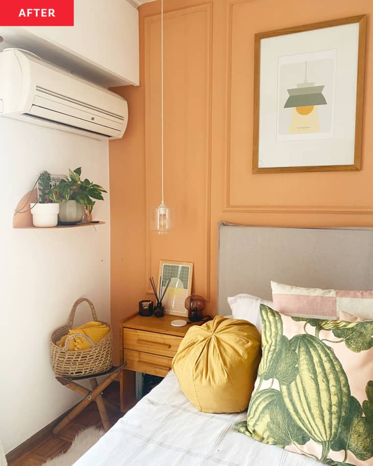 bedroom after repainting/remodel. Cantaloupe colored walls with decorative moulding, art prints of lamps, wood nightstand, white, ochre, blush, rose bedding with watermelon pattern pillow