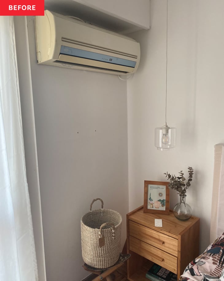 Corner of bedroom before repainting: white walls, wall heater/ac unit, wood nightstand